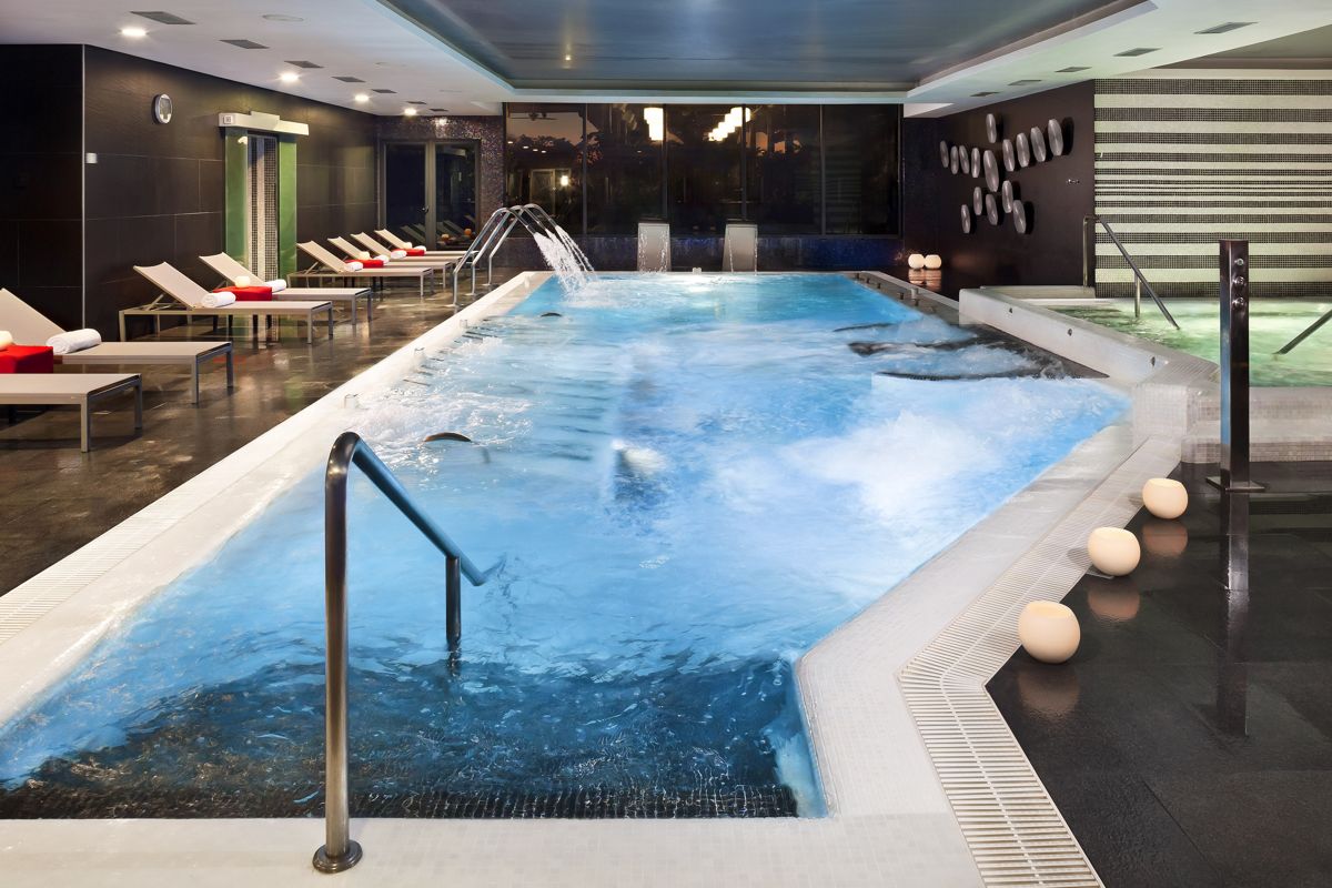 Piscina interna con lettini e getti d'acqua in un centro benessere a Tenerife.