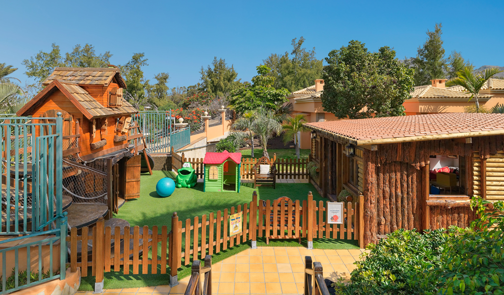 Giardino giochi per bambini a Tenerife, con casetta di legno e giochi colorati.
