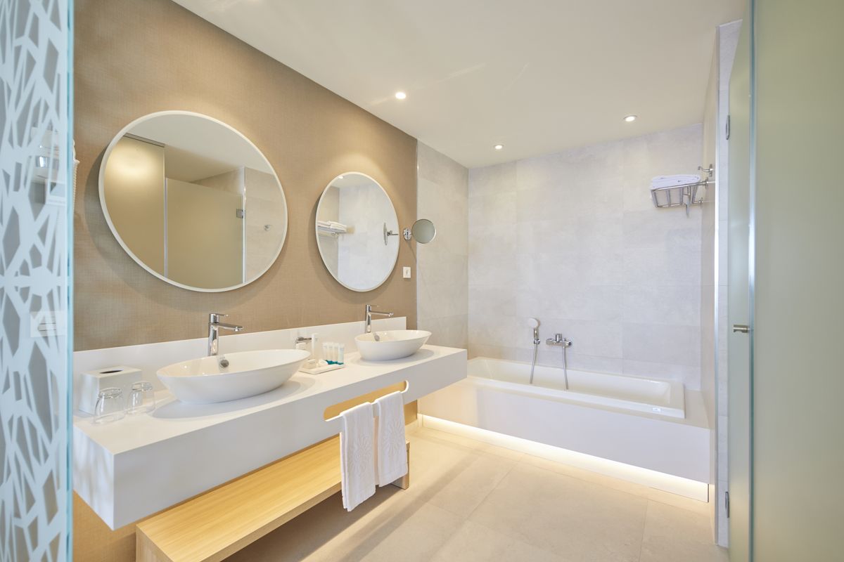 Bagno moderno con due lavandini, specchi rotondi e vasca a Tenerife.