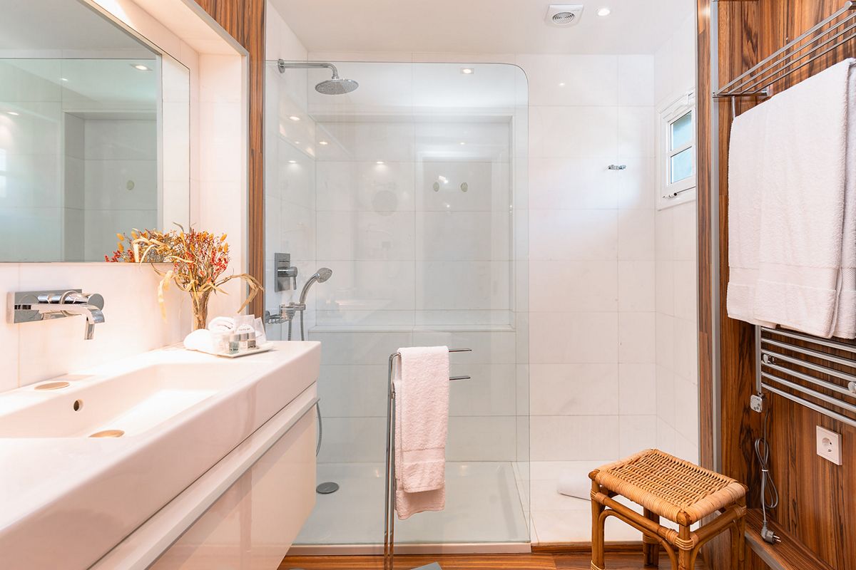 Bagno moderno con doccia in vetro, lavabo bianco e accenti in legno, Tenerife.