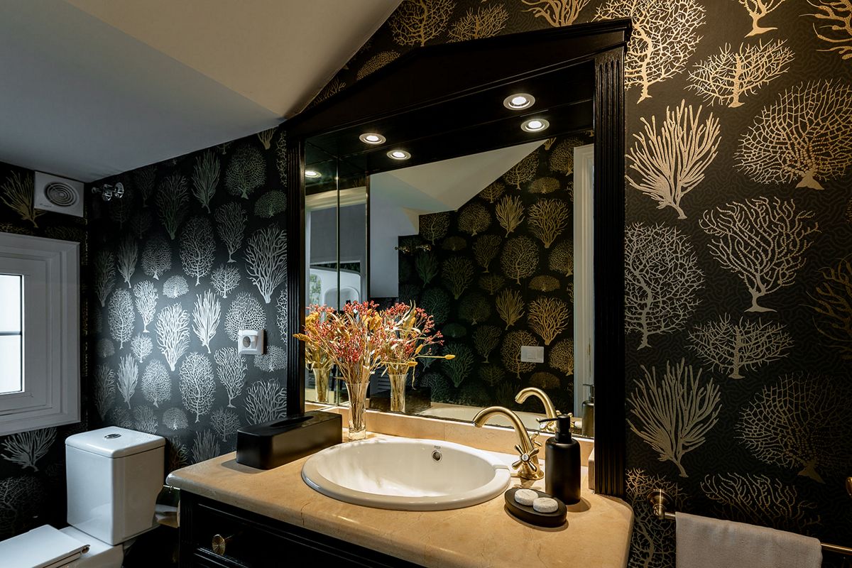 Bagno decorato con carta da parati corallo a Tenerife. Lavabo e specchio illuminato.