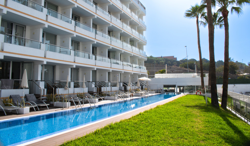 Edificio bianco a più piani e piscina con sdraio a Tenerife.