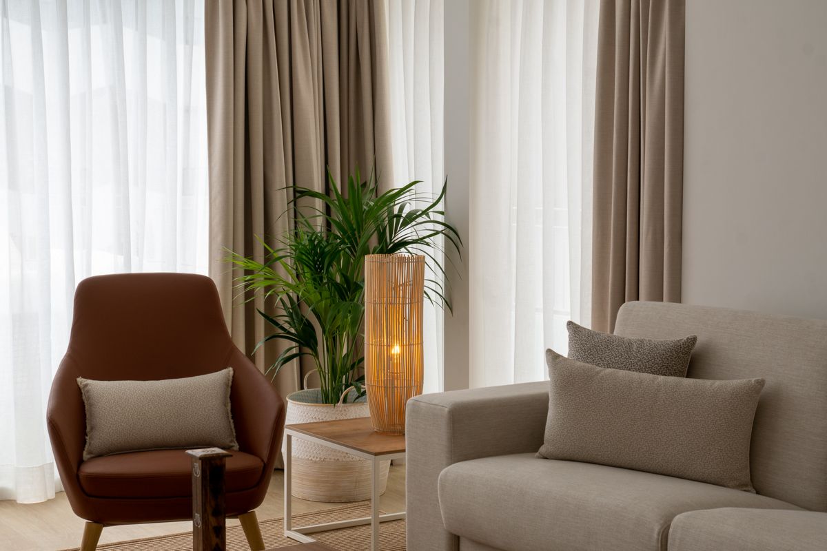 Poltrona marrone e divano beige con cuscini vicino a lampada e pianta a Puerto de la Cruz.