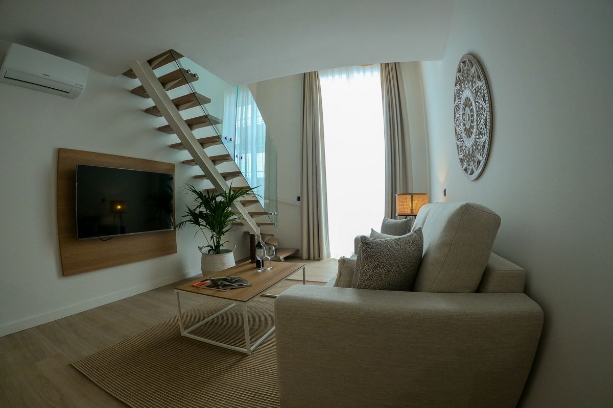 Soggiorno moderno con divano, tavolino, TV e scala a Tenerife.