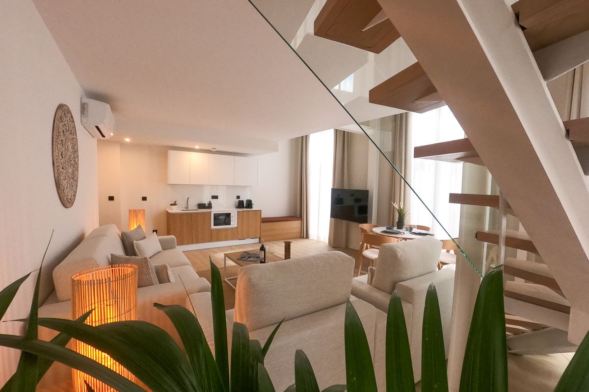 Soggiorno moderno con cucina aperta a Tenerife, scala e divani beige.