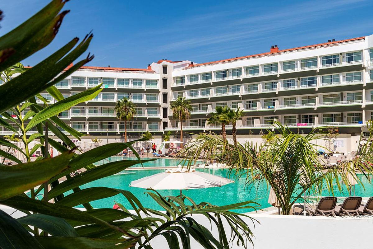 Edificio dell'hotel con piscina e palme a Tenerife sullo sfondo.