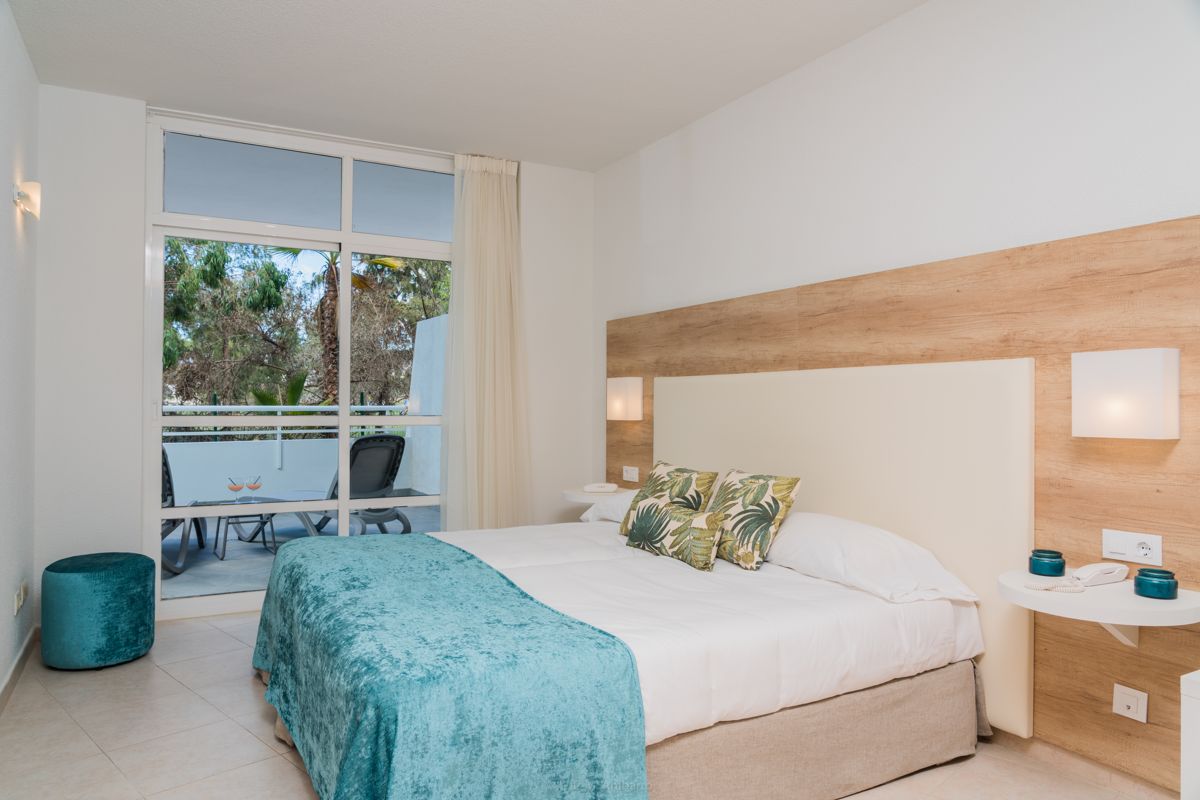 Camera da letto con letto matrimoniale, cuscini decorativi e balcone ad Adeje, Tenerife.