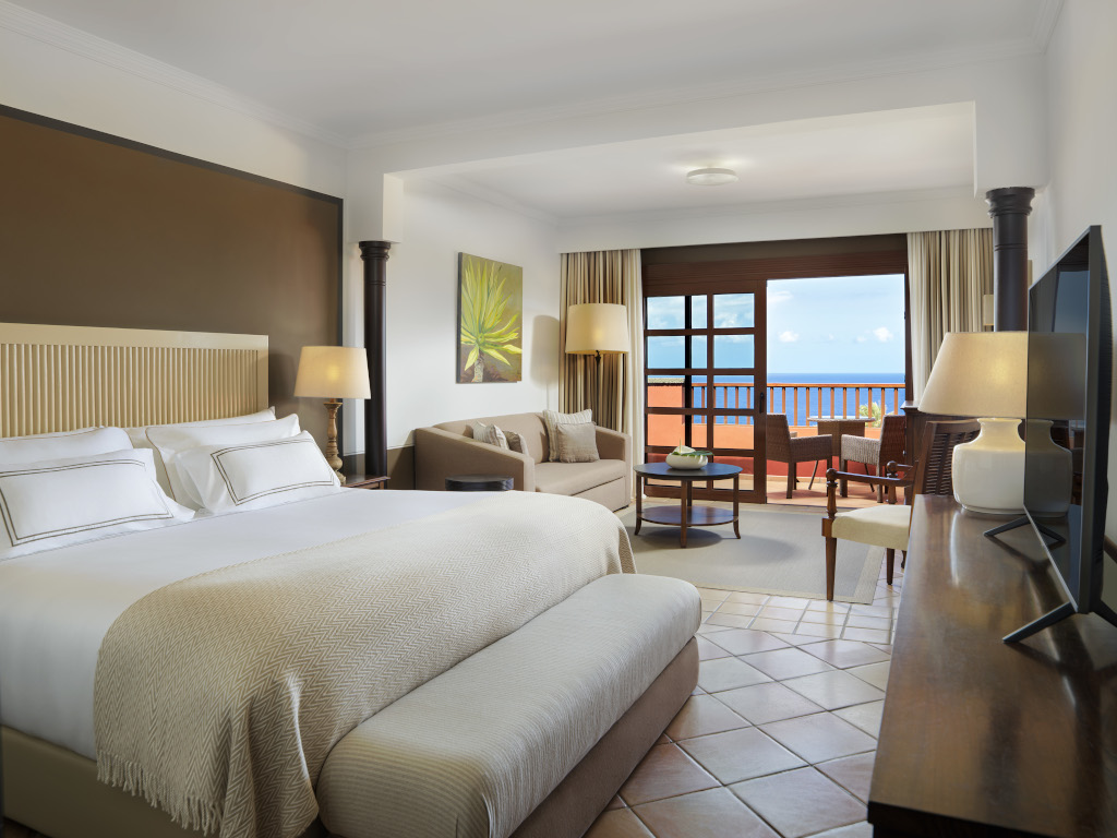 Camera d'hotel con letto matrimoniale, divano e vista mare a Tenerife.
