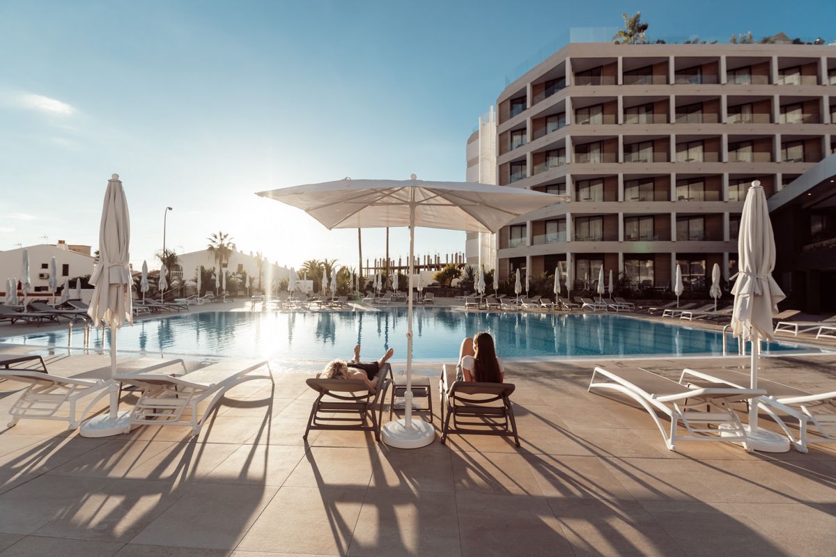 Piscina di un hotel a Tenerife con persone su lettini sotto ombrelloni.