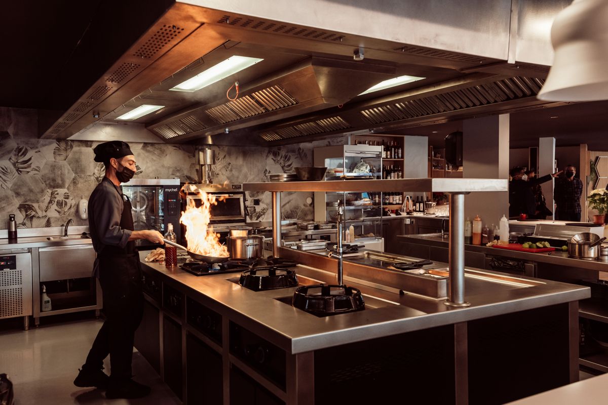 Chef che cucina alla fiamma in una cucina moderna a Tenerife.