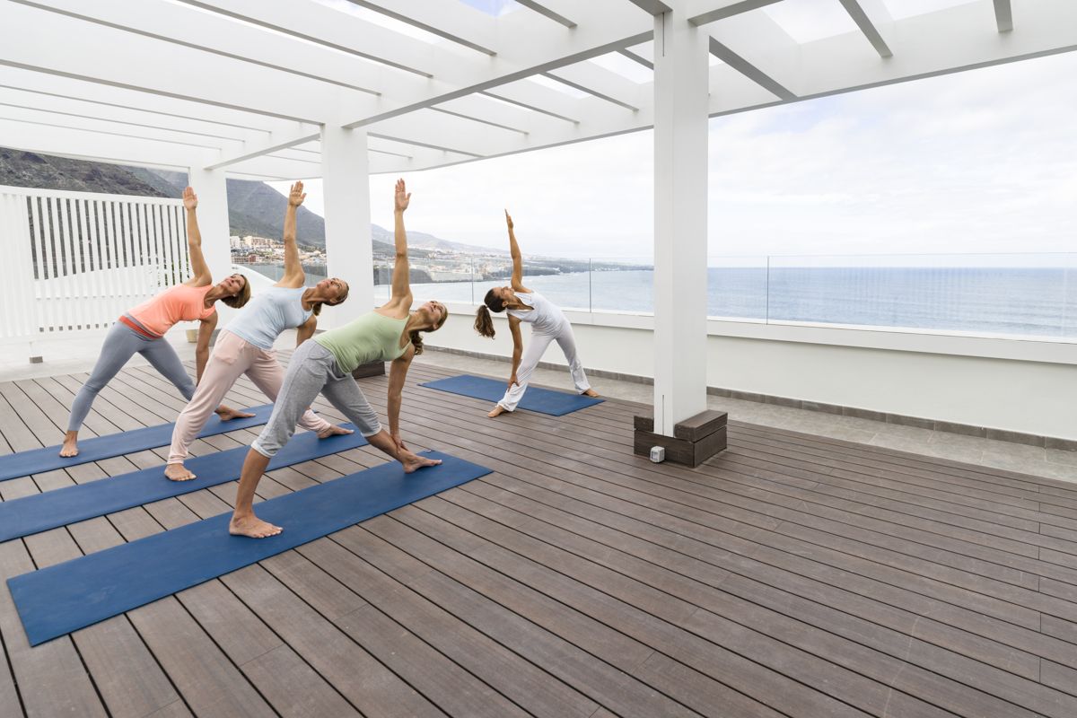 Persone facendo yoga su terrazza con vista mare a Tenerife.