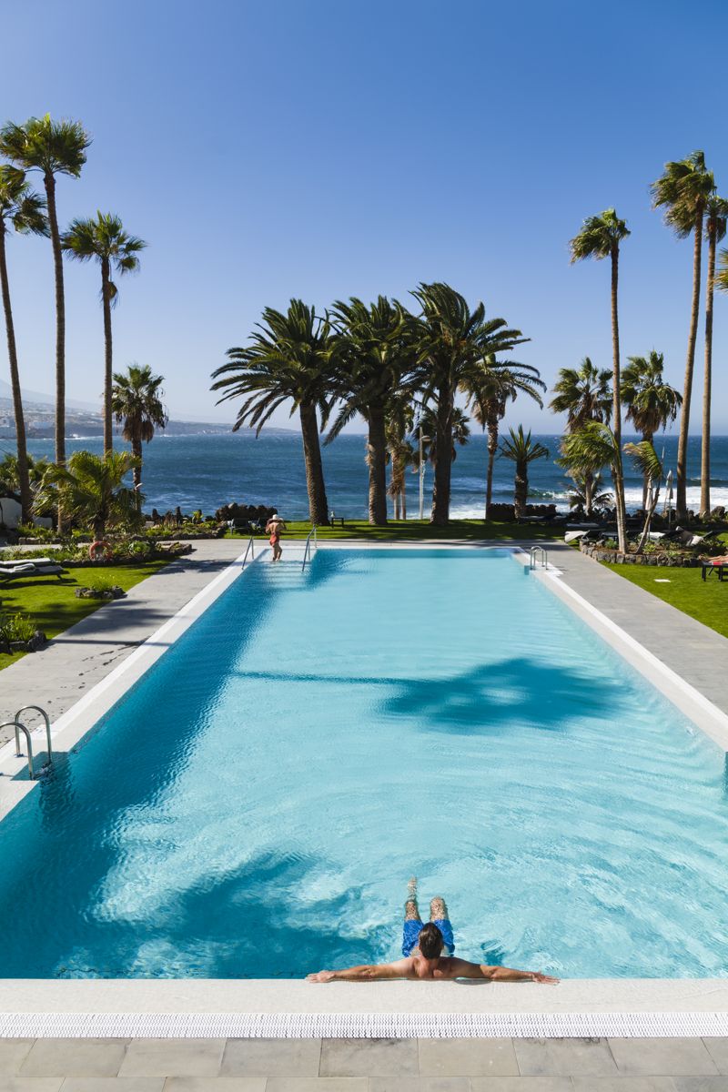 Piscina con palme e vista sull'oceano a Tenerife.