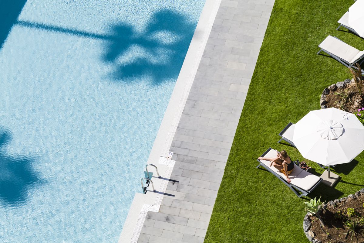 Piscina con sdraio e ombrelloni su prato a Tenerife.