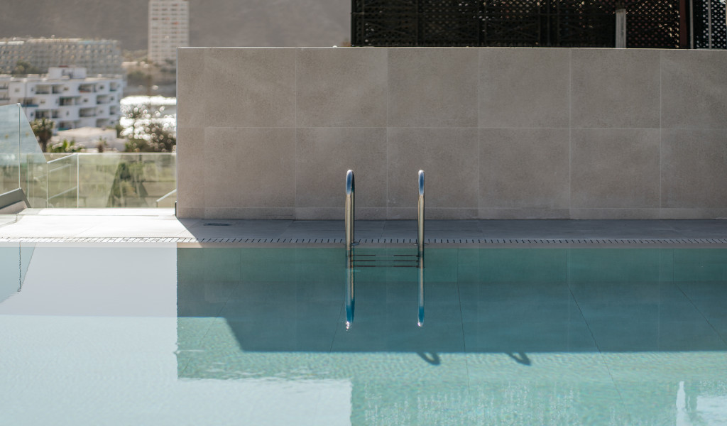 Piscina con scala e sfondo urbano a Tenerife.