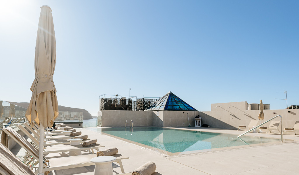 Piscina con sdraio e ombrelloni a Tenerife sotto un cielo azzurro.