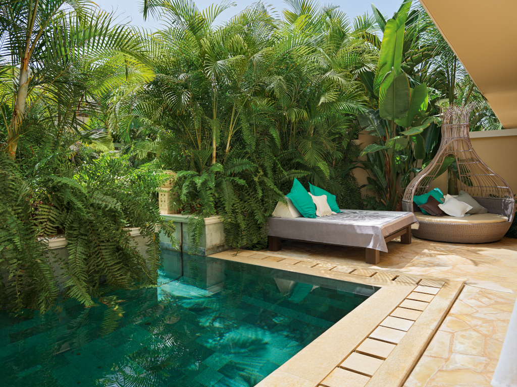 Piscina circondata da piante tropicali e zona relax con lettini a Tenerife.