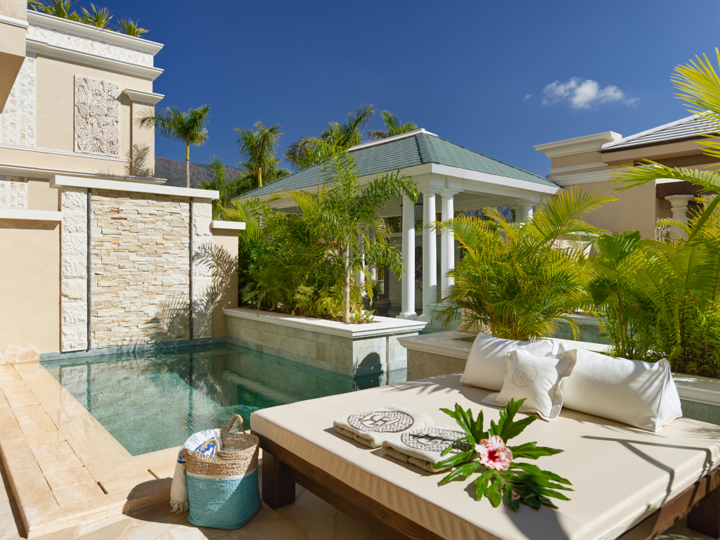 Piscina e lettino con cuscini e fiori in un resort a Tenerife.