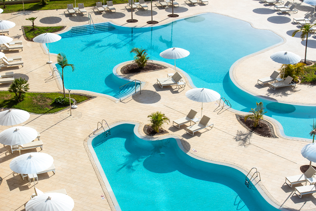 Piscina con lettini e ombrelloni bianchi in un hotel a Tenerife.