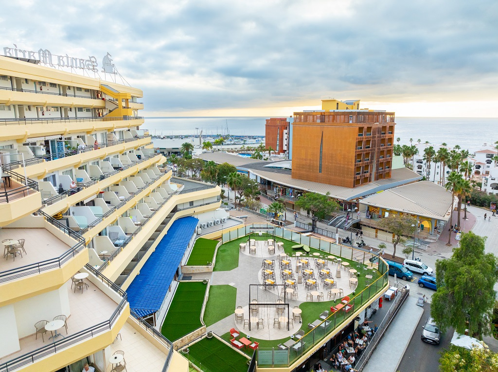 Hotel con balconi, area esterna con tavoli e vista mare a Los Cristianos, Tenerife.