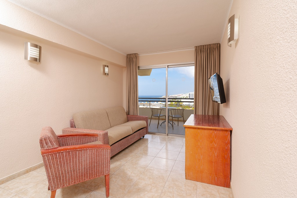 Soggiorno con divano, poltrona e TV, vista mare da un balcone a Tenerife.