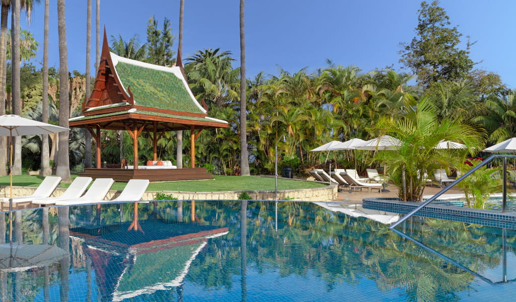 Gazebo tropical e piscina a Tenerife circondati da palme e sedie a sdraio.