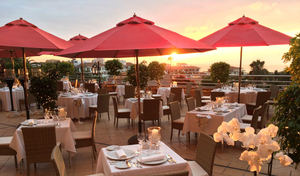 Ristorante con terrazza all'aperto sotto ombrelloni rossi al tramonto a Tenerife.