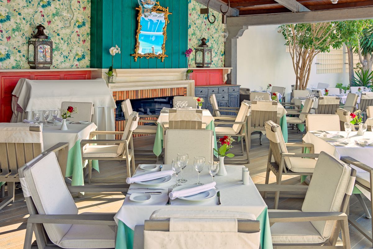 Ristorante con tavoli apparecchiati, decorazioni floreali e specchio a Costa Adeje.