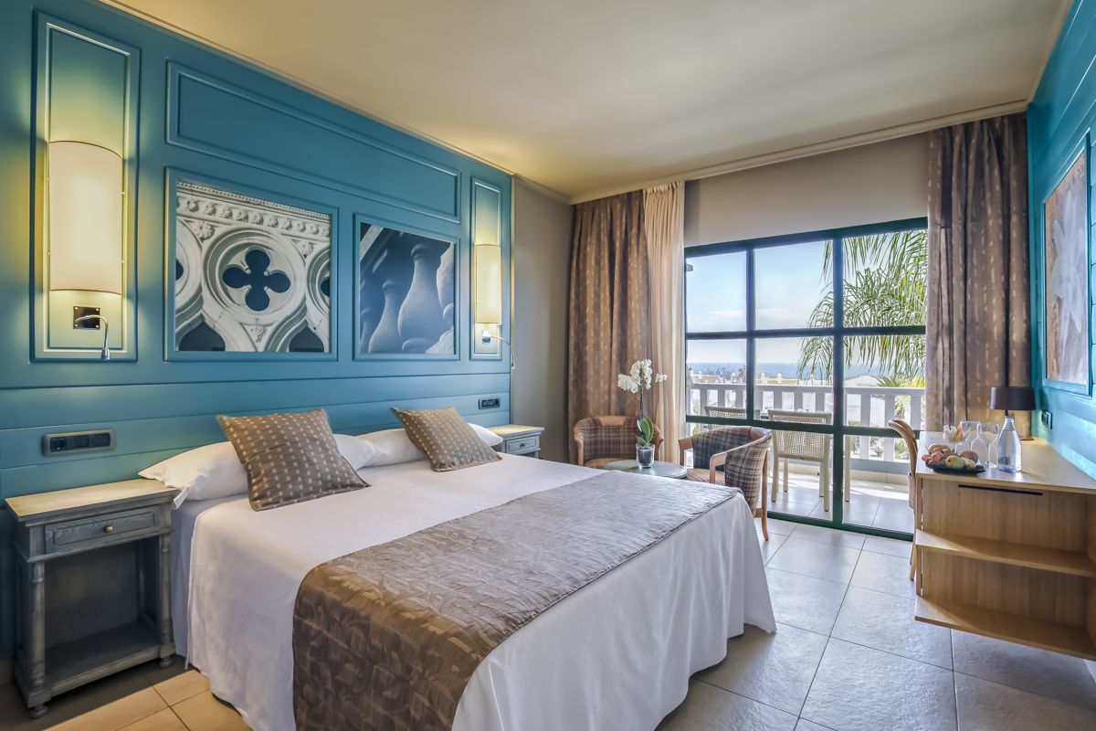 Camera d'hotel a Tenerife con letto matrimoniale, vista mare e decorazioni azzurre.