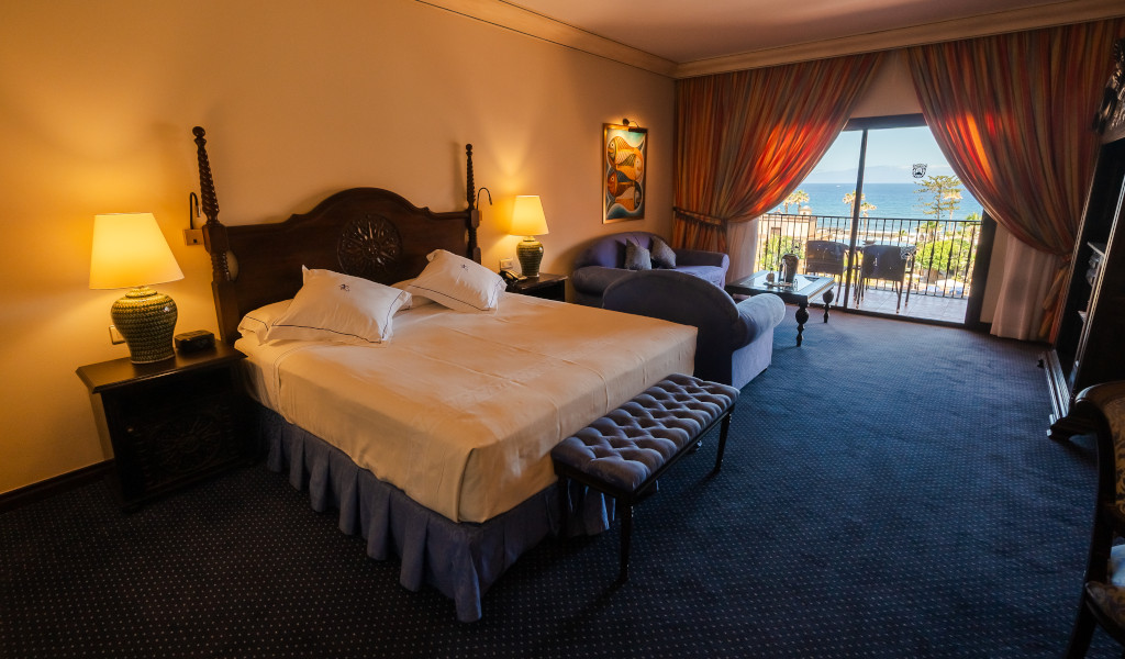 Camera d'albergo a Tenerife con letto matrimoniale, divano e vista mare dal balcone.