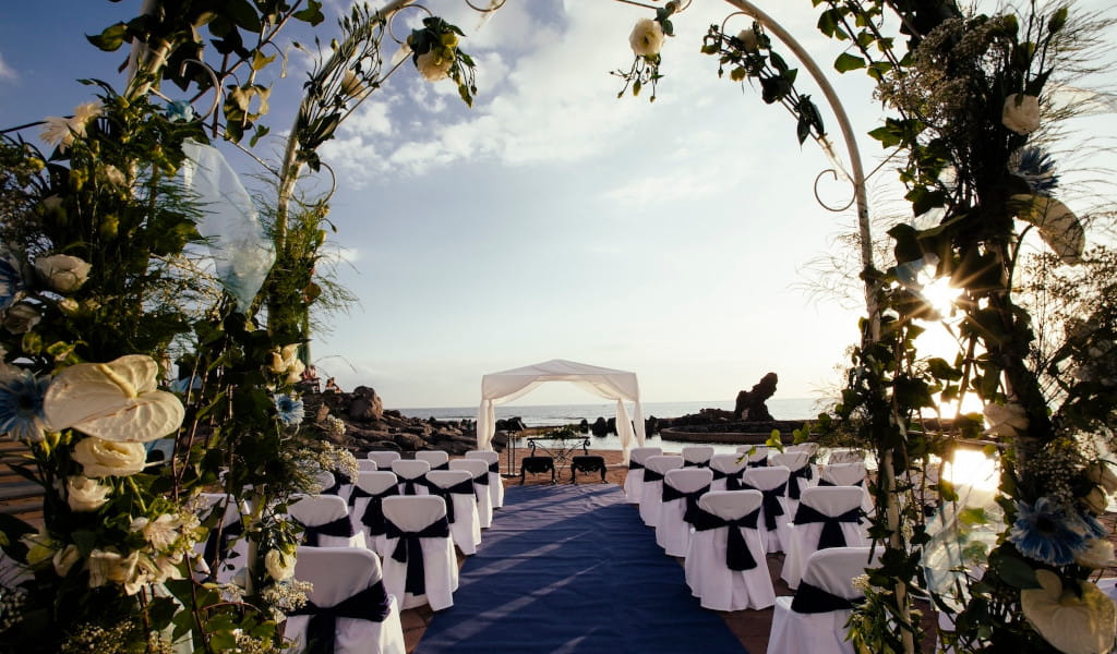 Cerimonia di matrimonio all'aperto a Tenerife con sedie bianche e vista mare.