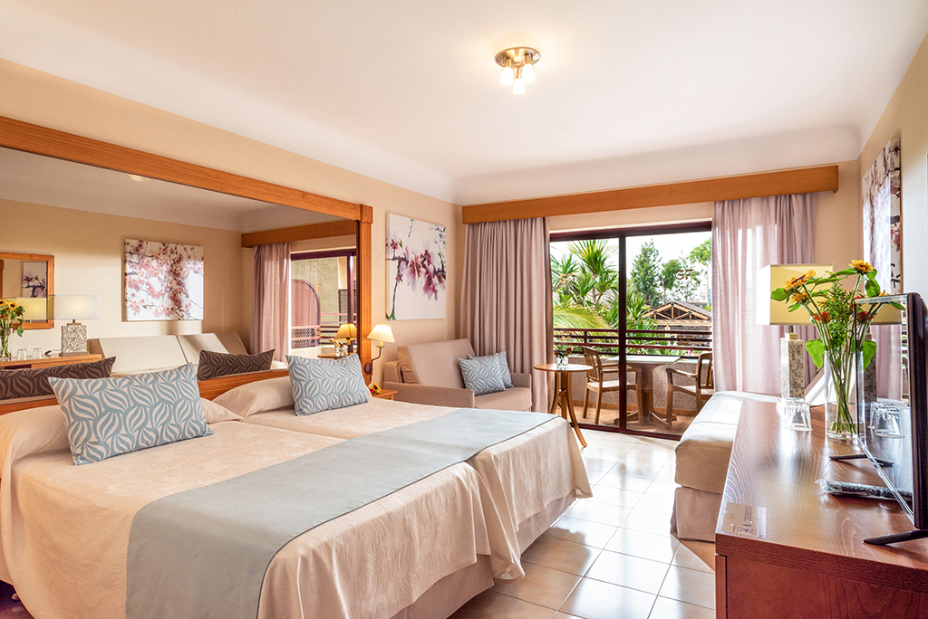 Camera d'hotel a Tenerife con letto matrimoniale e balcone con vista sul giardino.