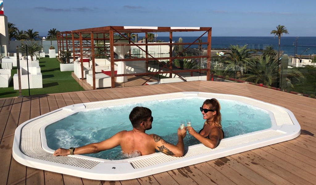 Due persone brindano in una vasca idromassaggio con vista sull'oceano a Tenerife.