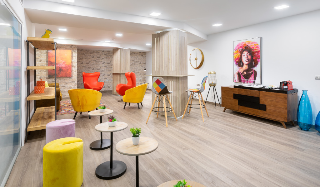 Area lounge con sedie colorate, tavoli e parete con arte pop nella sala Tenerife.