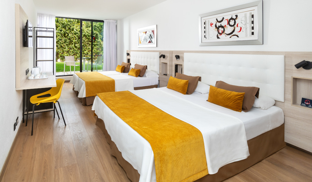 Camera d'albergo a Tenerife con due letti matrimoniali e vista giardino.