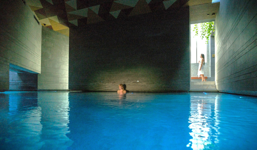 Piscina interna con persona seduta in acqua e donna accanto alla porta a Tenerife.