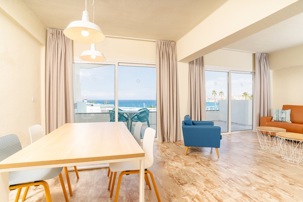 Sala luminosa con tavolo da pranzo, sedie, divano e vista mare a Tenerife.