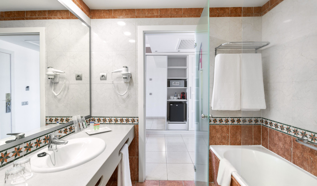 Bagno dell'hotel a Tenerife con lavabo, vasca e asciugamano bianco.