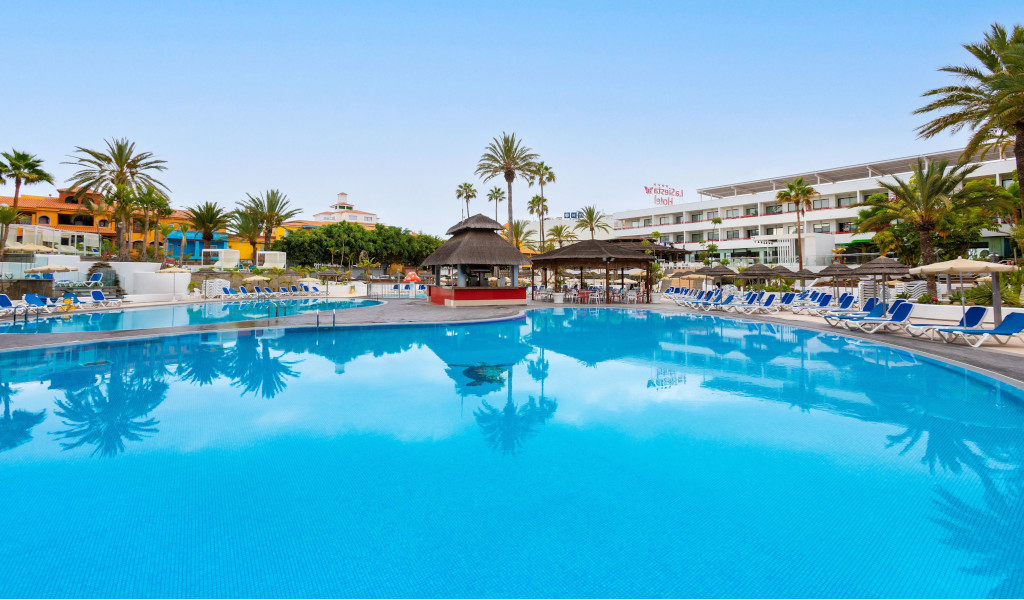 Piscina all'aperto con lettini e palme a Los Cristianos, Tenerife.