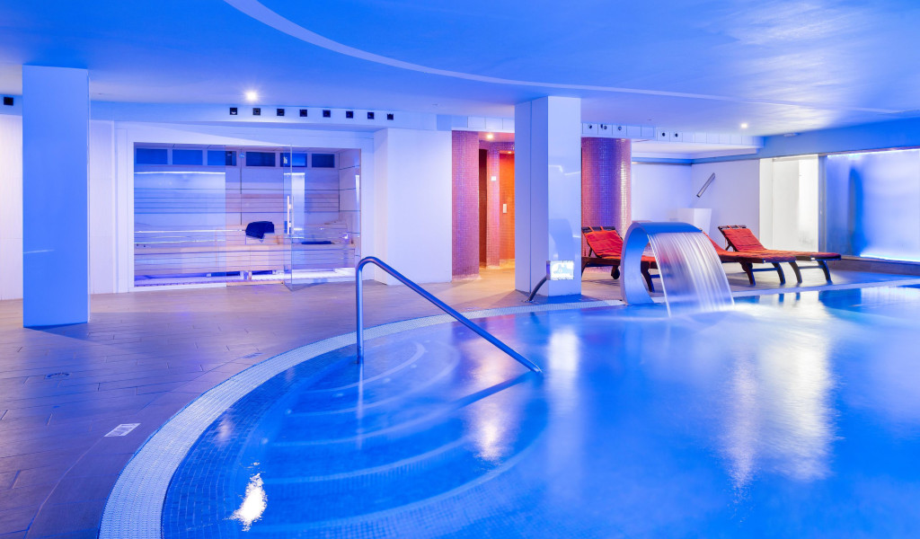 Piscina interna con cascate e lettini nel centro benessere a Tenerife.