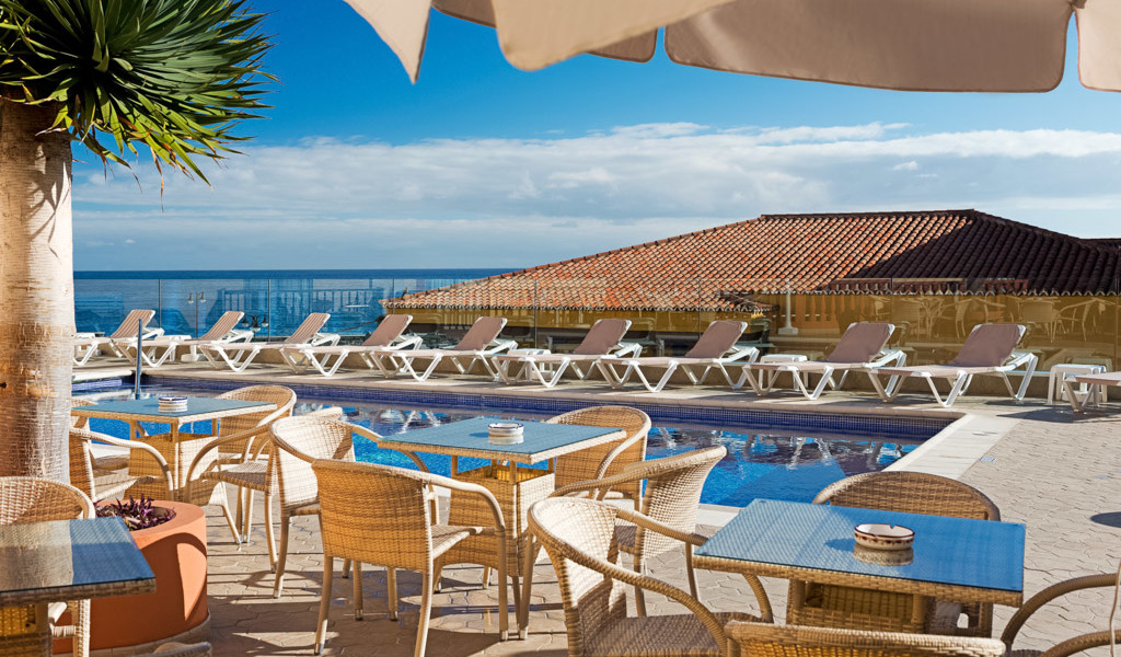 Sedie e tavoli vicino a piscina con lettini a Costa Adeje, Tenerife.