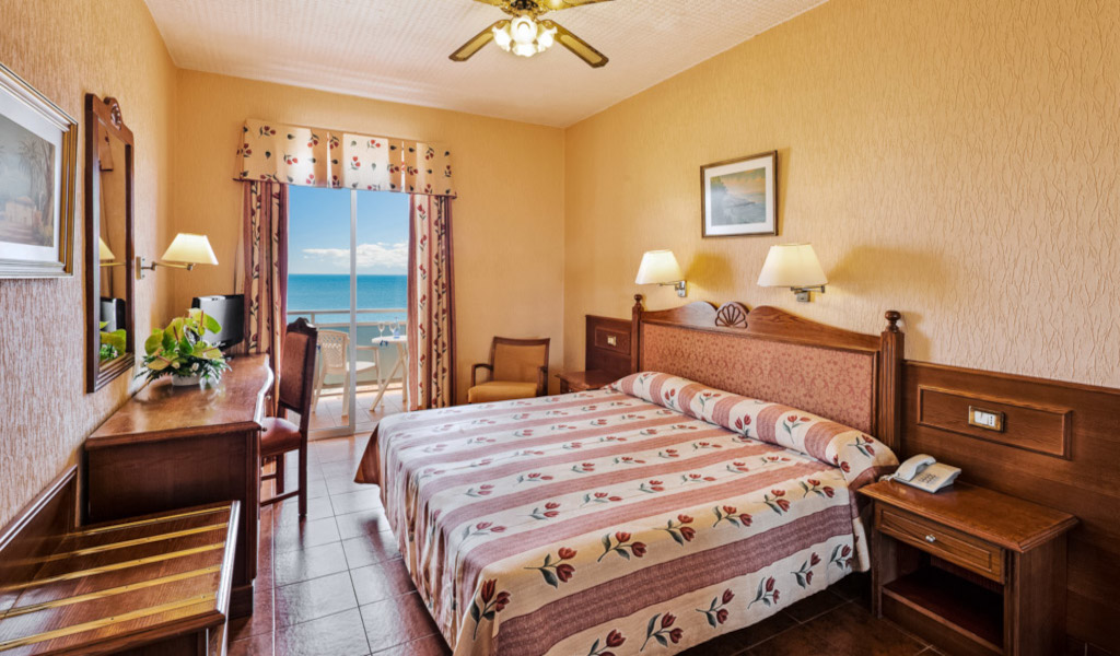 Camera d'hotel a Tenerife con letto matrimoniale e balcone vista mare.