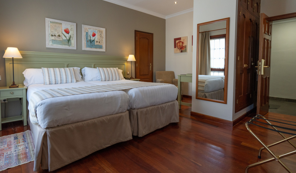 Camera d'albergo a Tenerife con due letti matrimoniali e mobili in legno.