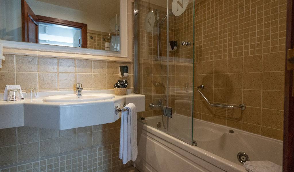 Bagno con vasca, lavabo bianco e specchio in un hotel a Tenerife.