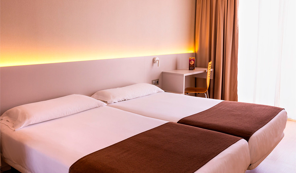 Due letti singoli con copriletti marroni e scrivania in hotel a Tenerife.