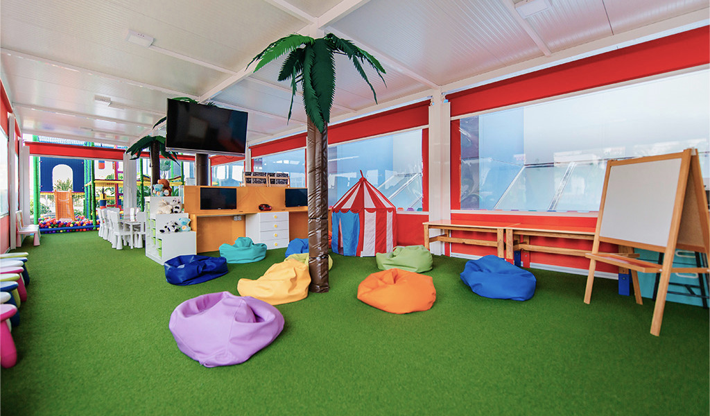 Area giochi bimbi con tappeto erboso, sedie colorate e tenda a Tenerife.