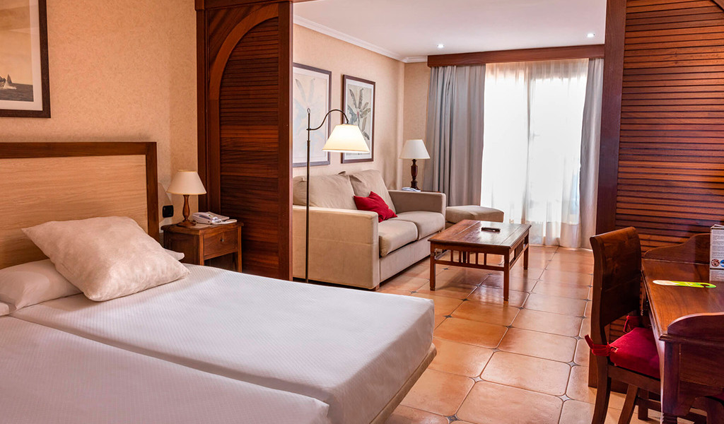 Camera d'albergo a Tenerife con letto, divano e tavolo in legno.