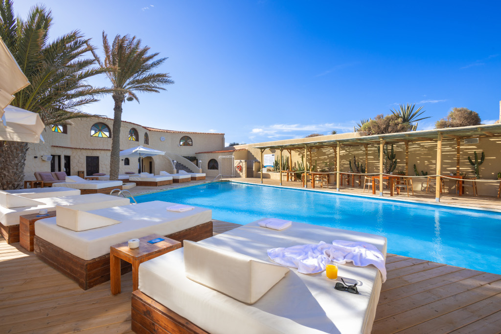 Piscina con lettini moderni e palme a Tenerife.