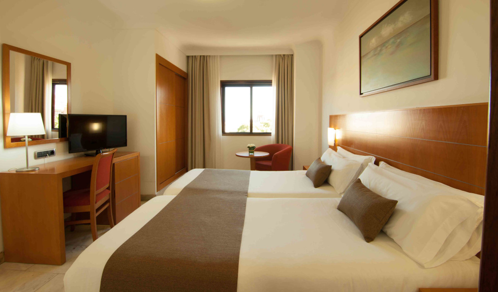 Camera d'hotel con due letti singoli, scrivania e finestra a Tenerife.