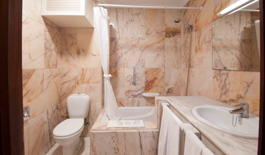 Bagno in marmo con doccia, lavabo e servizi igienici a Puerto de la Cruz.