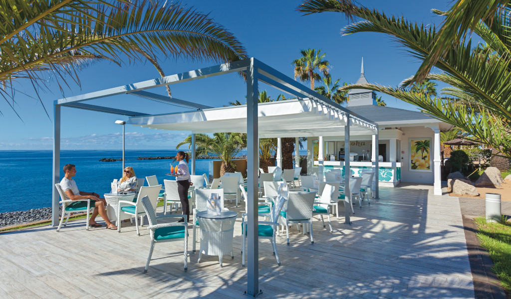 Terrazza sul mare a Tenerife con persone che si rilassano al tavolo.